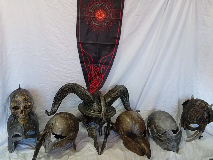 Sechs dunkle Fantasy-Helme vor einem Banner mit dem Auge