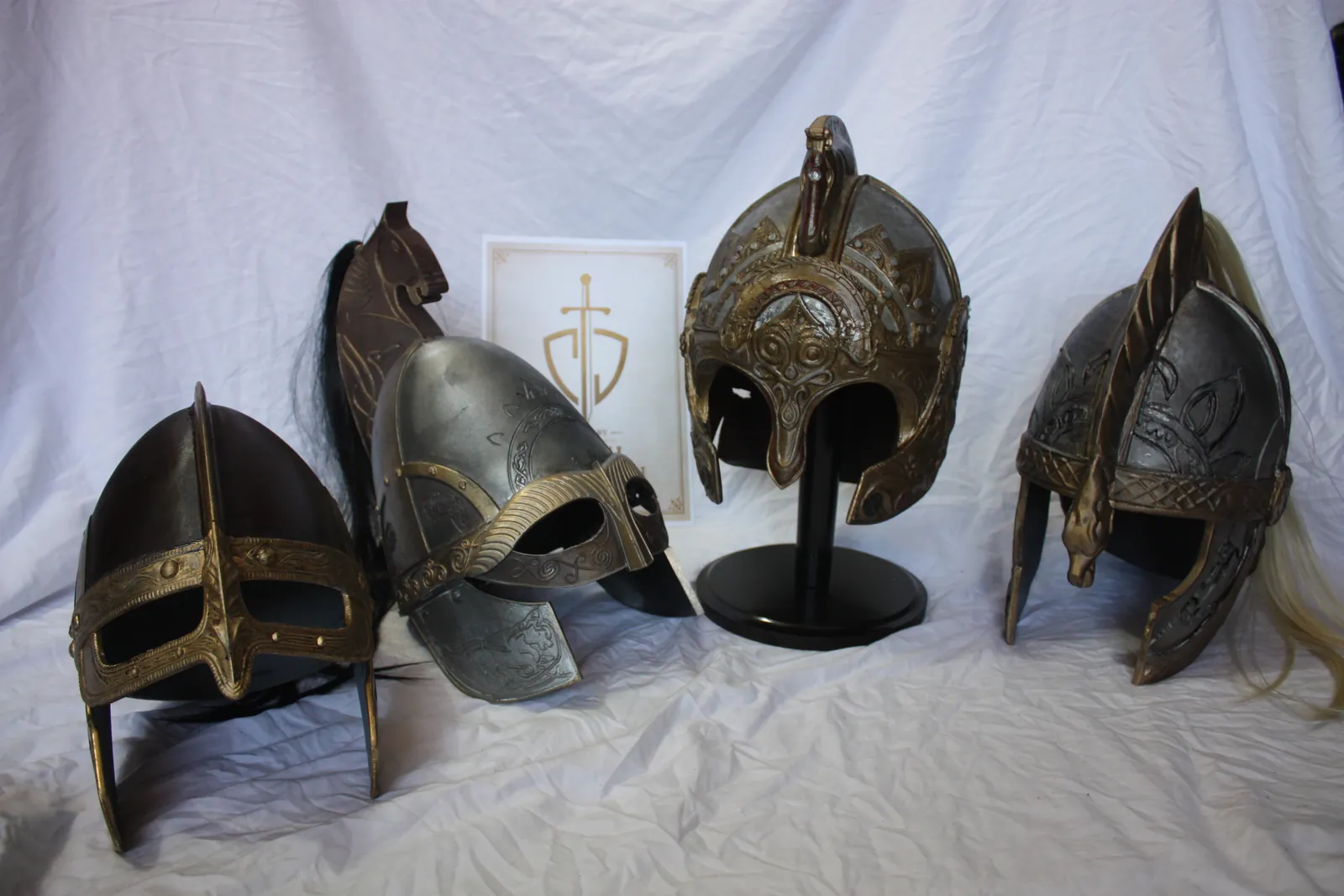 Four Rohirrim helmets on white fabric