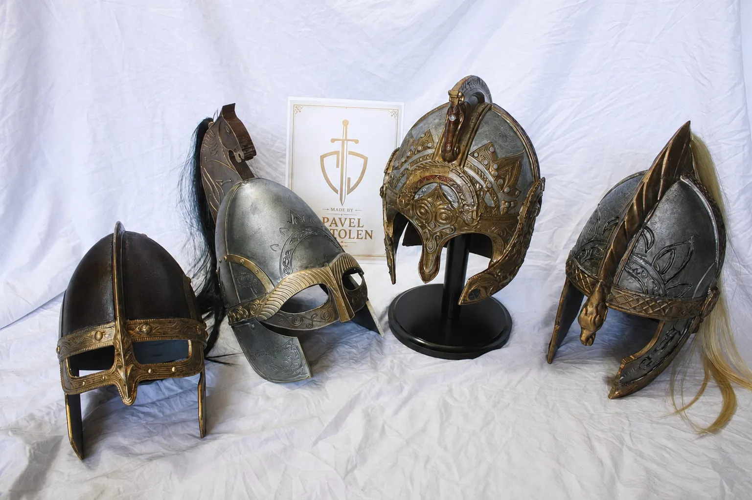 Four helmets with bronze ornaments on light fabric
