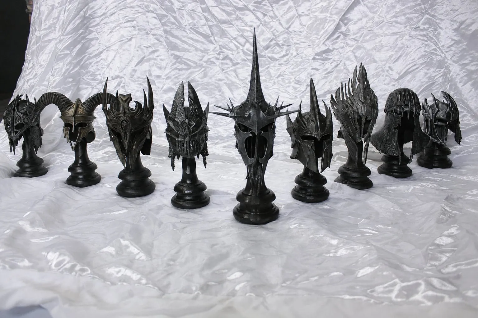 A row of dark fantasy helmets on black stands
