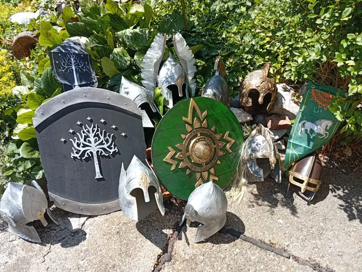 Schilde aus Gondor und Rohan mit Helmen in einem Garten