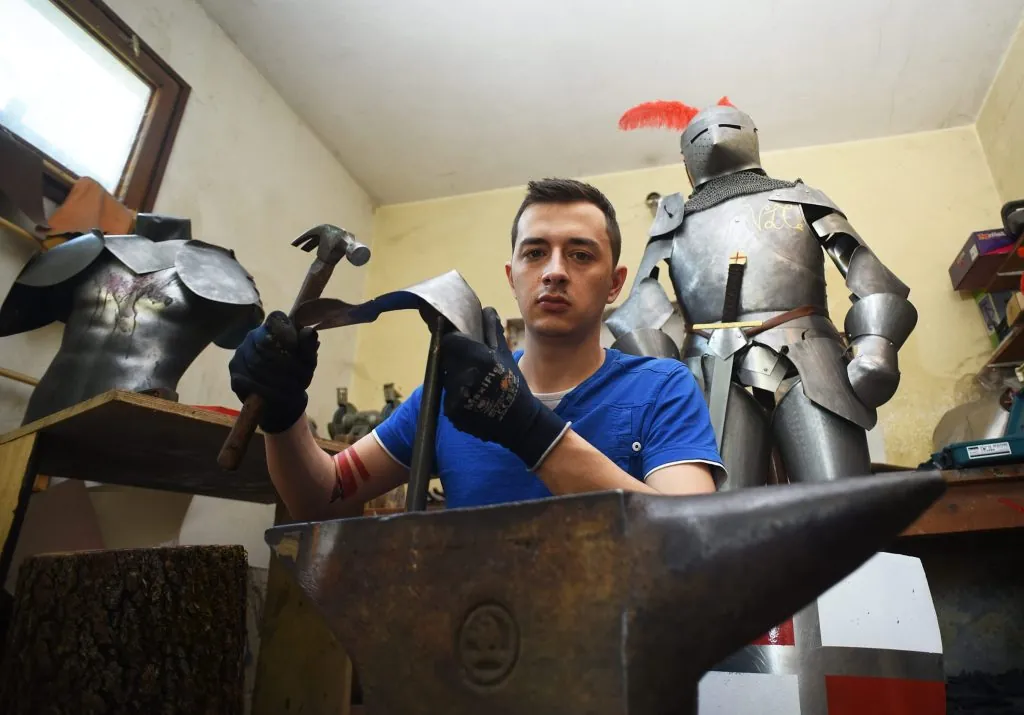 Pavel Butolen formt eine Metallplatte auf dem Amboss