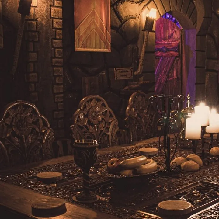 Medieval hall with carved chairs, candles and coats of arms on a stone wall
