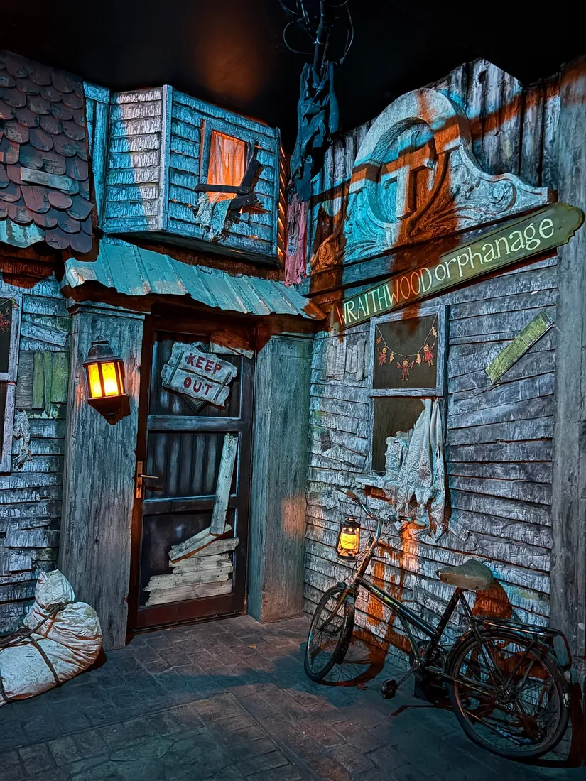 Entrance to a run-down orphanage with a sign, a lantern and an old bicycle
