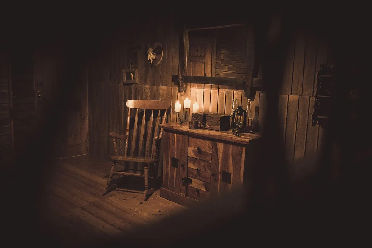 Wild West–style wooden room with a rocking chair, a chest of drawers and candles